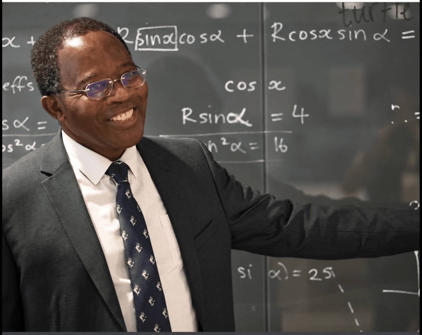 Black maths teacher standing beside a whiteboard